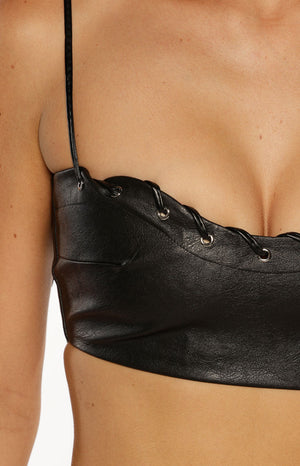 Close up of a black faux leather bralette top with lace-up details a bold top for a music Festival