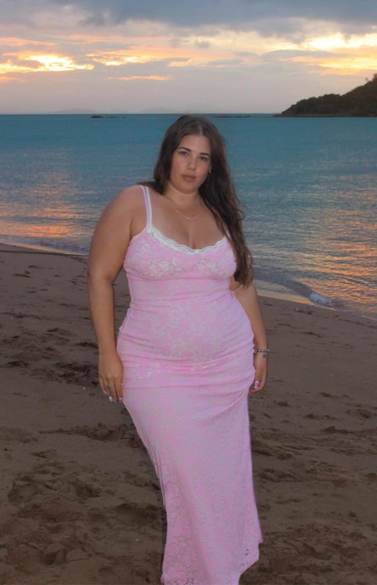 Side view of the fitted pink lace maxi dress with a white lace trim V-neckline and spaghetti straps