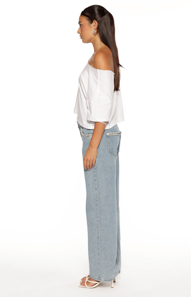 Side view of light wash denim low rise jeans with diamante trim along the waistband and a wide leg fit