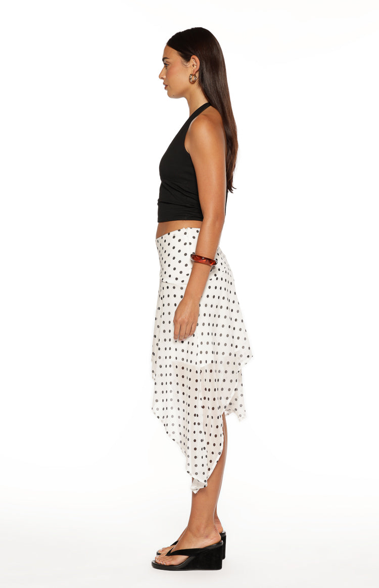 Side view of a white polka dot midi skirt, showing its relaxed fit and asymmetrical hanky hem