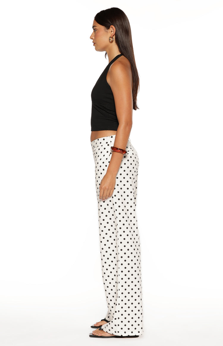Side view of white low waist pants with black polka dots and a straight leg fit