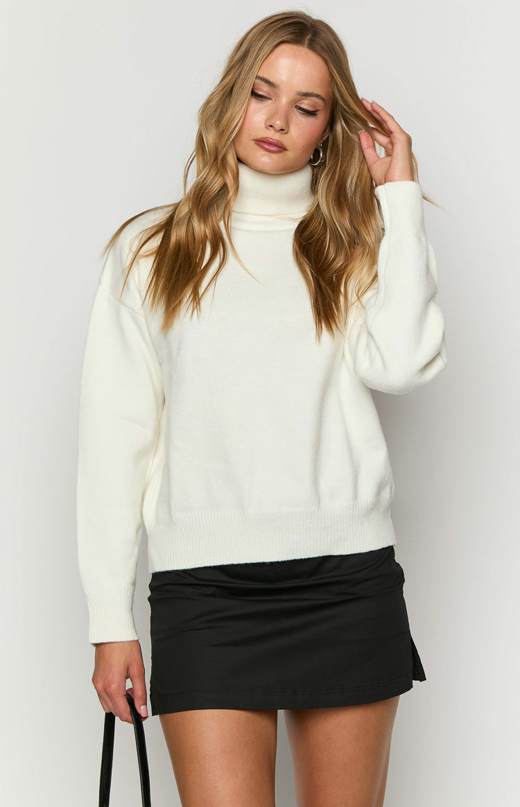Cream knit sweater with a high turtleneck, soft texture, and ribbed hem and cuffs
