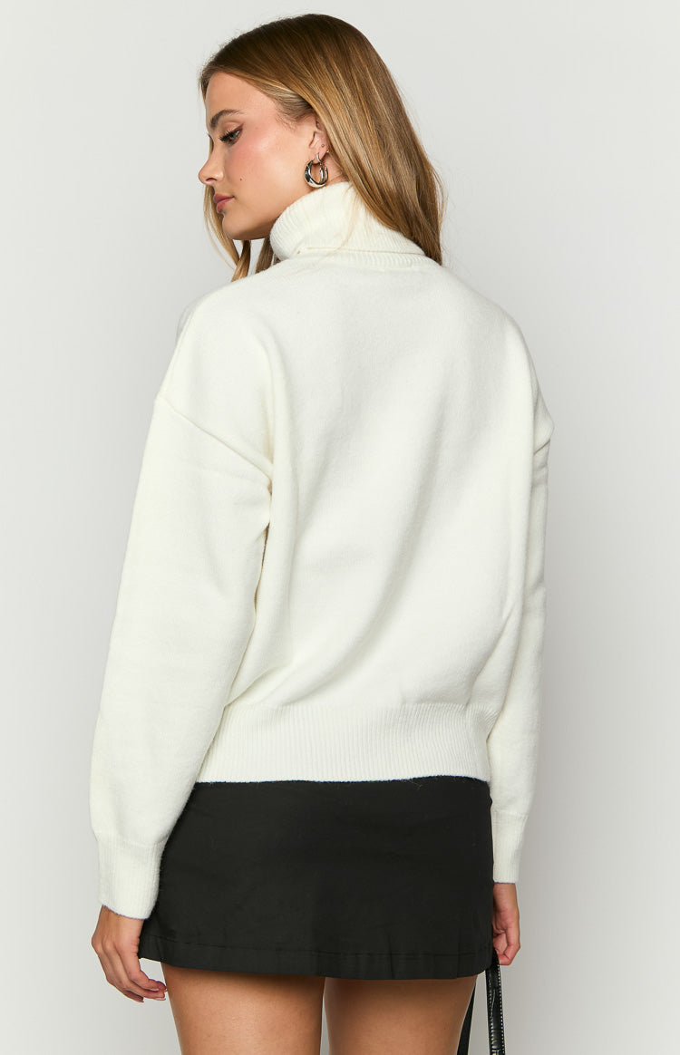 Rear view of a cream knit sweater with a high turtleneck, relaxed long sleeves, and a ribbed hem
