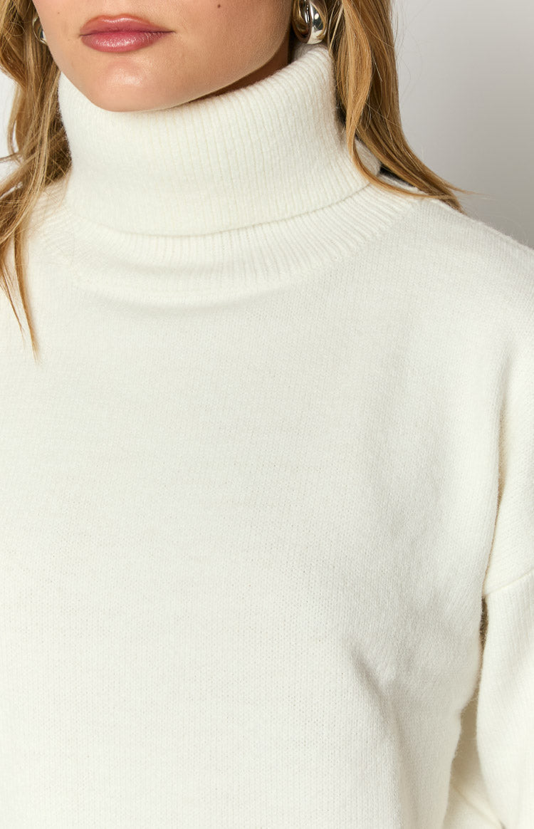 Close-up of the cream turtleneck sweater showing the ribbed neck and soft knit texture
