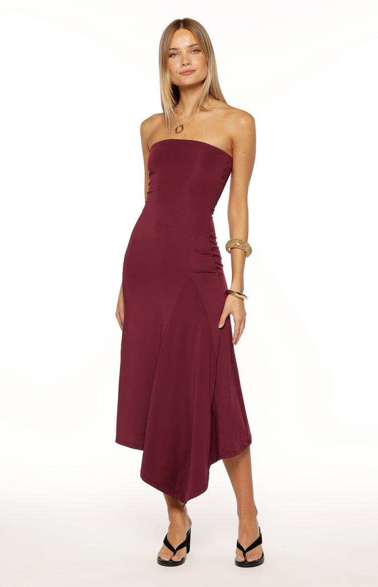 Plum strapless midi dress with a fitted bodice, ruched side detail, and a flowing asymmetrical handkerchief hem