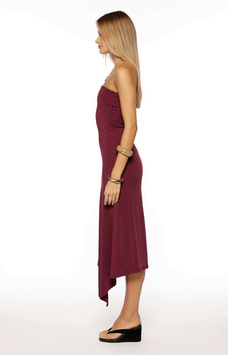 Side view of a plum strapless midi dress with a fitted bodice and an asymmetrical hemline