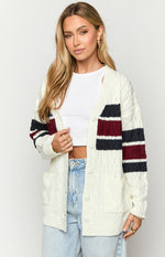 Open cream cable knit cardigan with navy and burgundy stripes, white buttons, and front patch pockets