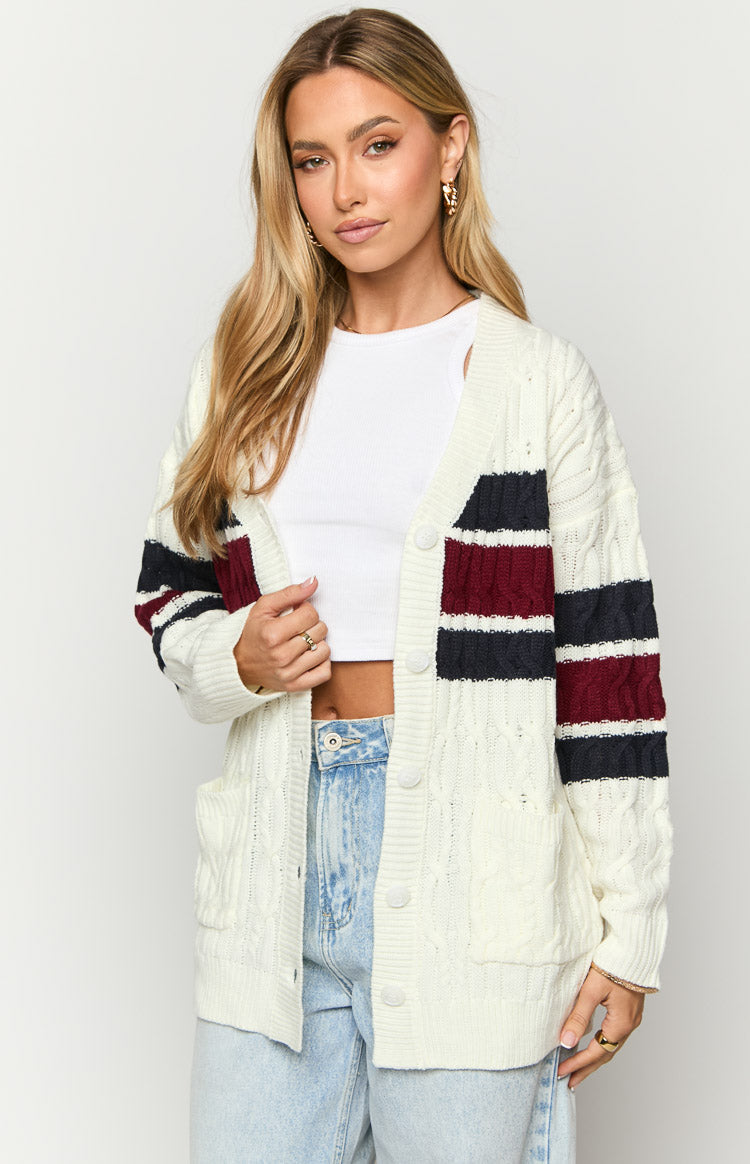 Open cream cable knit cardigan with navy and burgundy stripes, white buttons, and front patch pockets