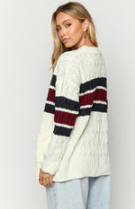 Side view of a cream cable knit cardigan with navy and burgundy stripes on the long sleeves
