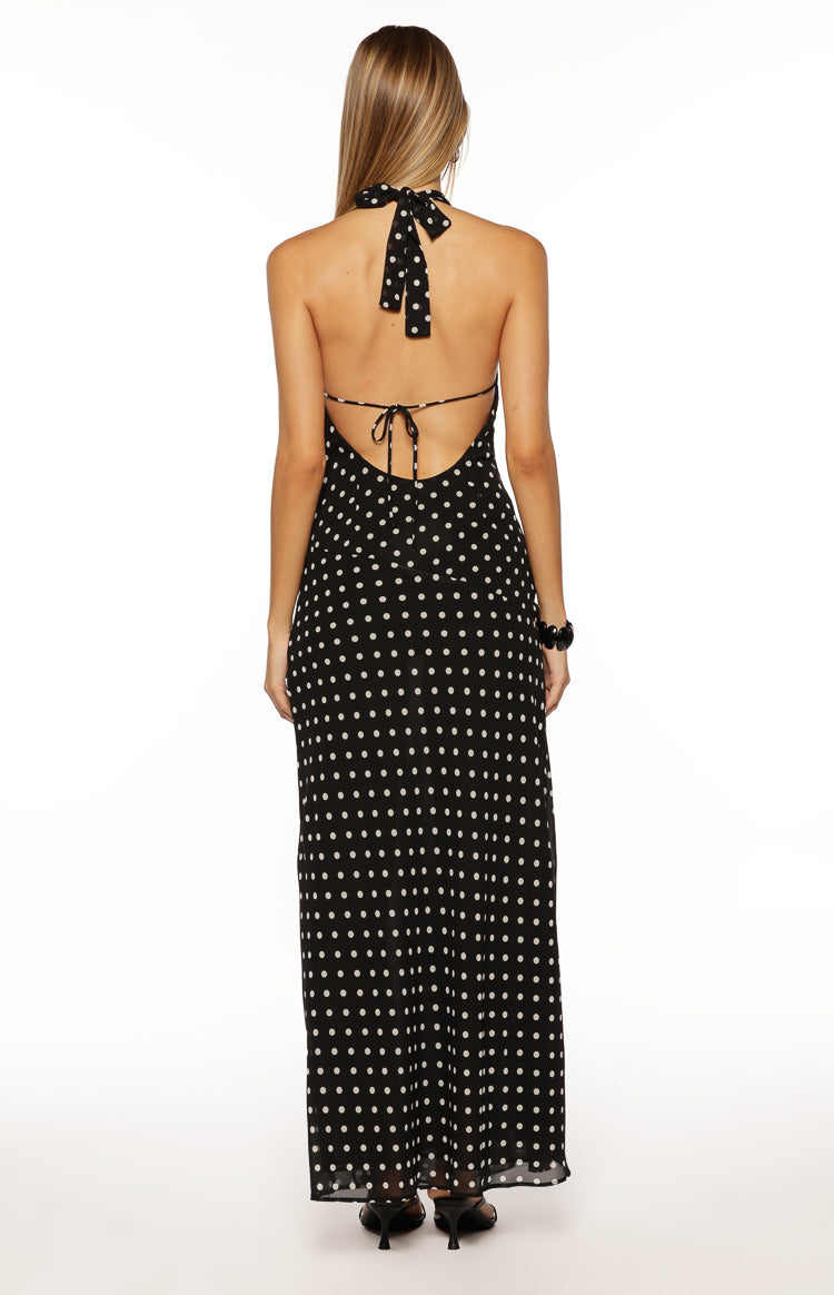 Rear view of a black polka dot maxi dress showing the halter neck tie and low open back with tie detail