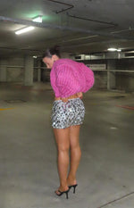 Side view of a cropped pink chunky knit cardigan with voluminous sleeves