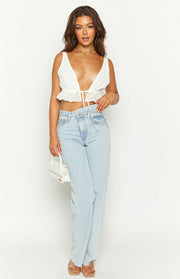 White sleeveless crop top with a deep V-neckline, tie-front closure, and a ruffled hem