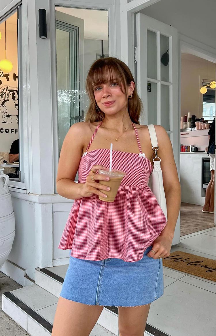 Front view of a red gingham halter top with a square neckline and gathered peplum hem