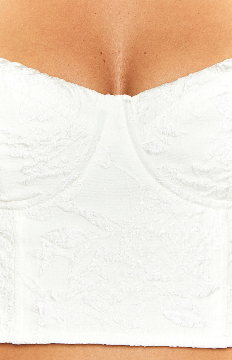 Close-up of the white corset top's structured bust cups with an embossed floral texture