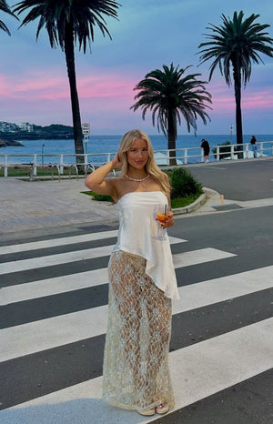 White strapless satin top with a draped fit and an asymmetric hemline, worn for an evening out