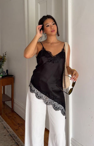 Beginning Boutique Ziva Black Satin Lace Trim Asymmetrical Top black satin V-neck top with lace trim and asymmetrical hem
