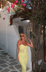 Yellow maxi skirt with sheer mesh panel at the hip styled with a matching strapless tie-front top outdoors