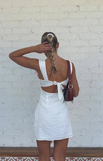 Rear view of a white striped mini dress with a tie-back closure and side waist cutouts