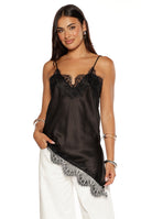 A model wearing a black satin camisole with a V-neckline and thin spaghetti straps featuring black lace trim on the bust and a dramatic asymmetrical white lace panel on the hemline.